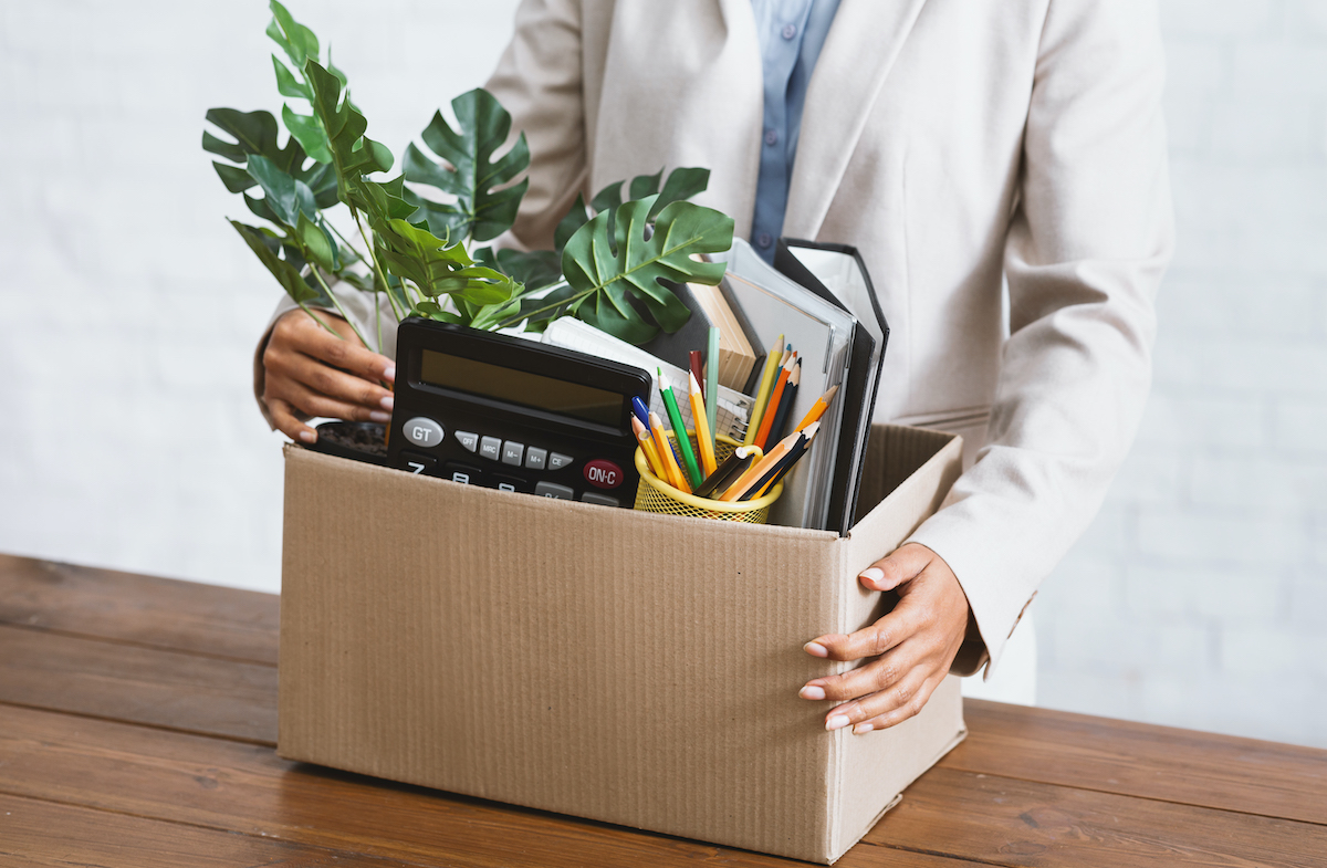 a recently unemployed worker packs their office supplies into a box