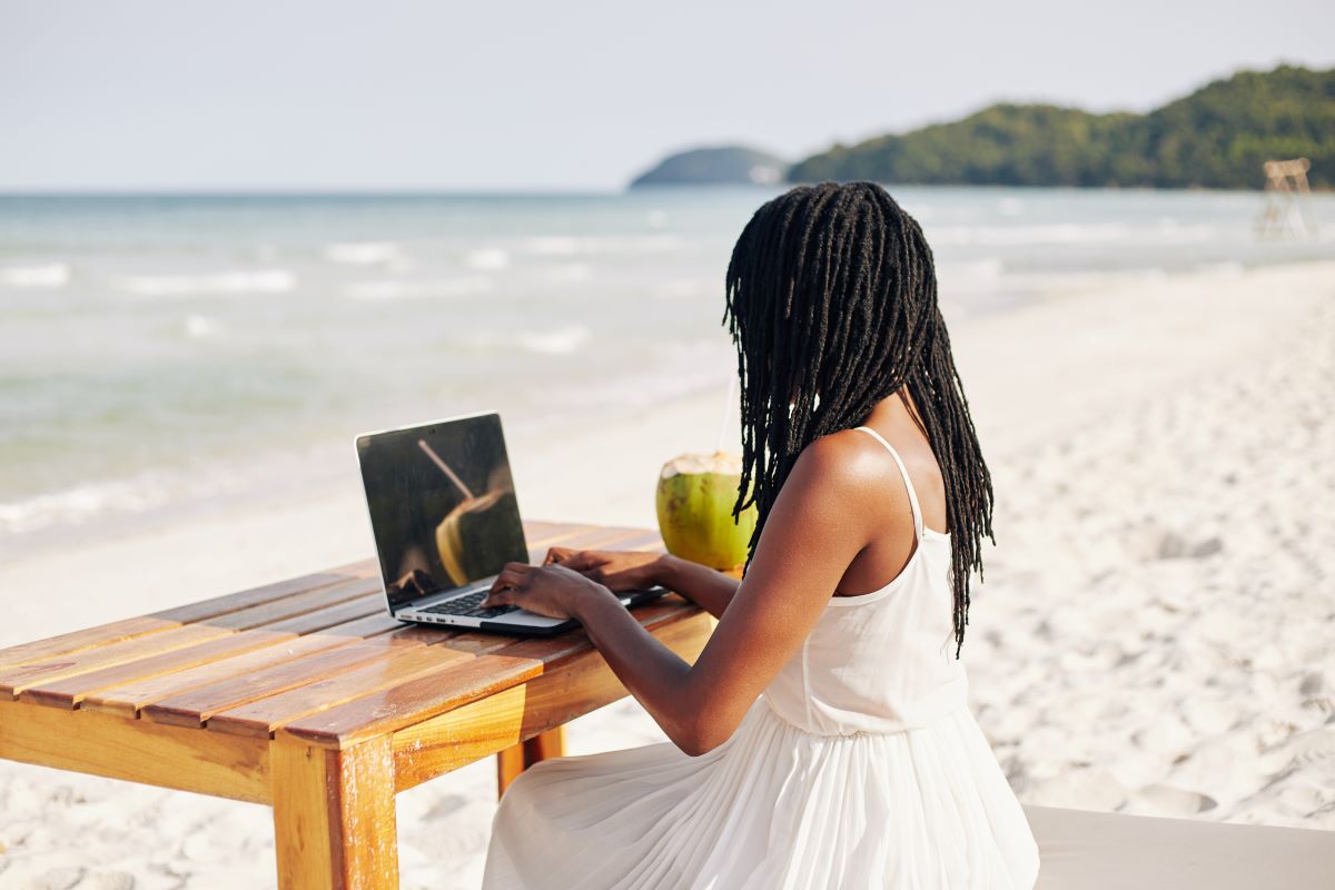 A remote employee works at a table at the beach